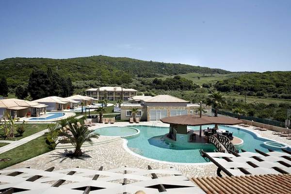 Aussenansicht des Olympia Golden Beach Resorts mit Pools, Liegen und Pavillon.