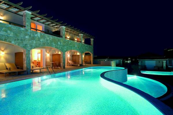 Nachtansicht des Swimmingpools des Olympia Golden Beach Resorts mit beleuchteten Gebäuden.