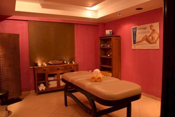 Massageraum im Olympia Golden Beach Resort mit roten Wänden und Massagetisch.