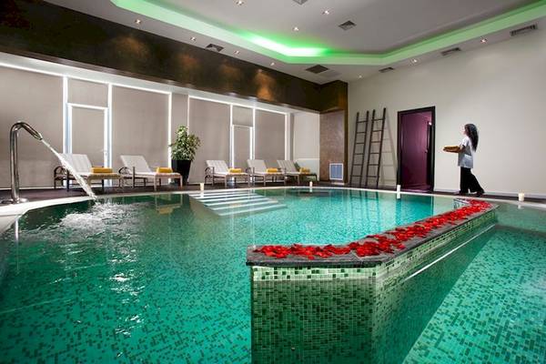Ein Schwimmbad im Olympia Golden Beach Resort mit roten Rosenblättern entlang des Randes.