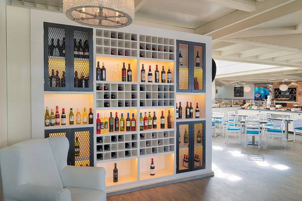 Restaurant im H10 Suites Lanzarote Gardens mit Weinregal und Tischen.