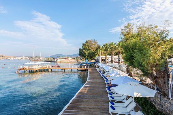 Strandbereich des Labranda TMT Bodrum Hotels mit weißen Sonnenliegen und Sonnenschirmen.