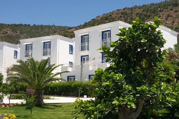 Außenansicht des Labranda TMT Bodrum Hotels mit weißen Gebäuden, blauen Fensterrahmen und umliegenden Pflanzen.