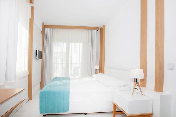 Schlafzimmer im LABRANDA TMT Bodrum Hotel mit weißem Bett, blauer Decke, zwei Lampen und weißem Nachttisch.