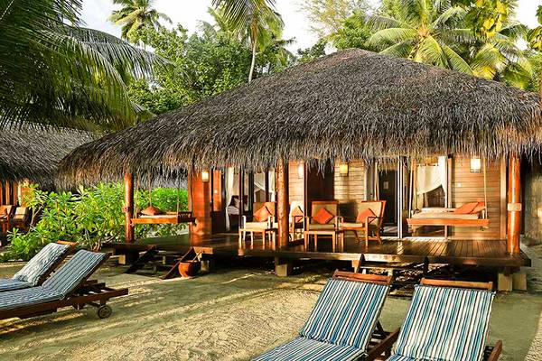 Strandhütte des Medhufushi Island Resorts mit Blick auf das Meer und tropische Bäume