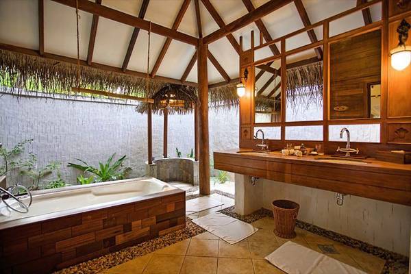 Ein Badezimmer im Medhufushi Island Resort mit einer Badewanne, zwei Waschbecken und einer Toilette.