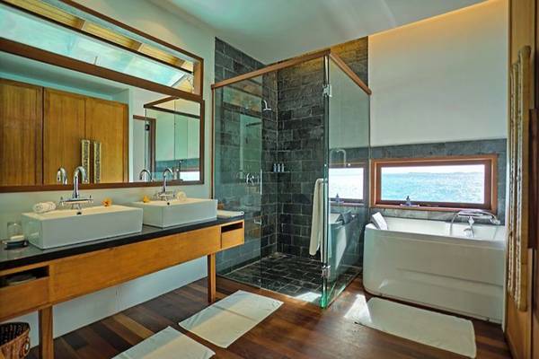 Badezimmer im Medhufushi Island Resort mit zwei Waschbecken und einer Badewanne mit Meerblick.