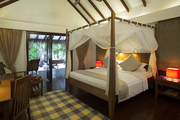 Schlafzimmer im Medhufushi Island Resort mit Himmelbett, Schreibtisch und Fernseher.