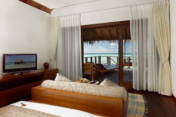 Innenansicht einer Suite im Medhufushi Island Resort mit Blick auf das Meer und eine Terrasse.