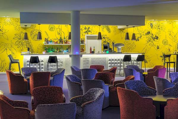 Lobby des H10 Suites Lanzarote Gardens Hotels mit gelben Wänden und vielen bunten Stühlen.