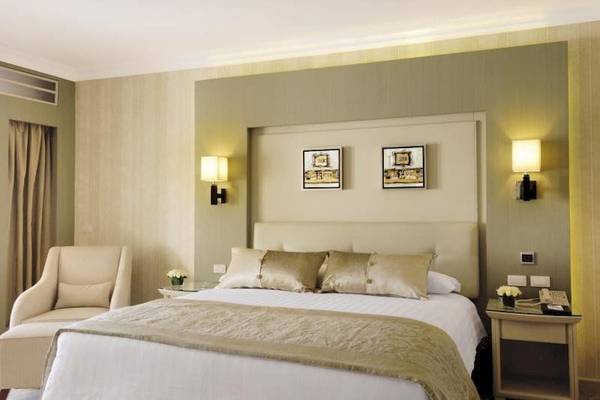 Schlafzimmer im KaiSol Romance Resort Sahl Hasheesh mit Bett, Sesseln, Nachttischen und Bildern an der Wand.