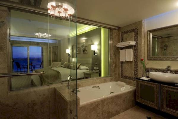 Das Badezimmer des KaiSol Romance Resort Sahl Hasheesh mit Badewanne, Dusche und Blick auf das Bett.