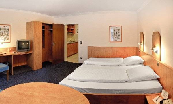 Hotelzimmer im Hamburg Mitte mit Schreibtisch, Fernseher, Betten und Stühlen.