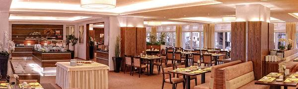 Restaurant im Hamburg Mitte Hotel mit vielen Tischen und Stühlen, dekoriert mit Pflanzen und Lampen.
