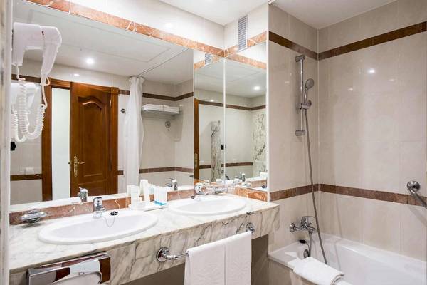 Ein Badezimmer mit zwei Waschbecken und einer Badewanne im Bahia Principe Sunlight Costa Adeje Hotel.