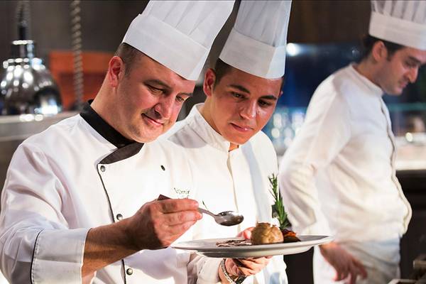 Einige Köche im weißen Kochgeschirr bereiten Essen in einem Hotelrestaurant vor.