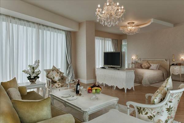 Innenansicht einer Suite im Maxx Royal Belek Golf Resort mit eleganten Möbeln, einem großen Bett und einem Wohnzimmerbereich.