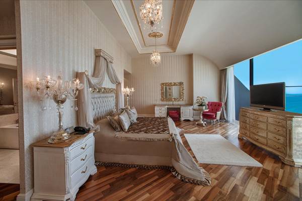 Luxuriöses Schlafzimmer im Maxx Royal Belek Golf Resort mit großem Bett, Kristalllampen und Meerblick.