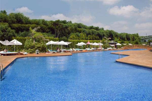 Ein großer Swimmingpool im Maxx Royal Belek Golf Resort mit Loungestühlen und Sonnenschirmen.
