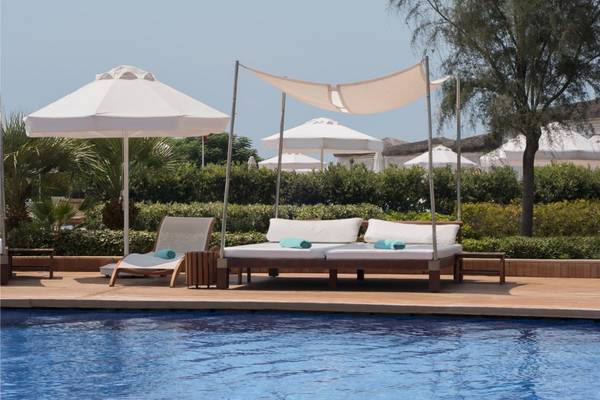Pool-Loungebereich im Maxx Royal Belek Golf Resort mit Sonnenbetten und Sonnenschirmen.