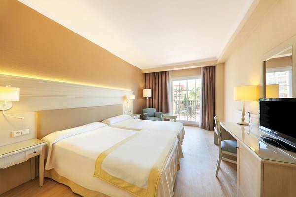 Doppelzimmer im Iberostar Malaga Playa Hotel mit zwei Betten, Nachttischen und einem Schreibtisch.
