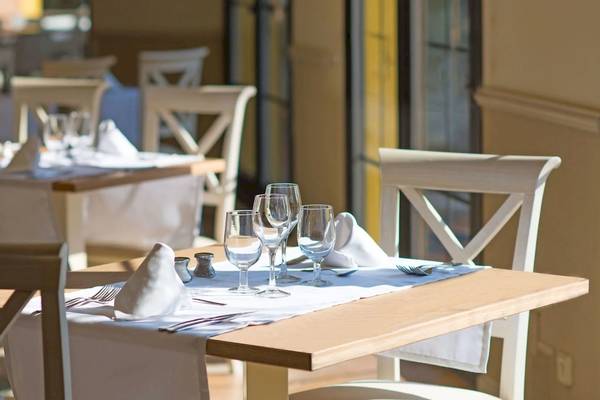 Ein gedeckter Tisch in einem hellen Restaurant mit Wein- und Wassergläsern, Besteck und Servietten.