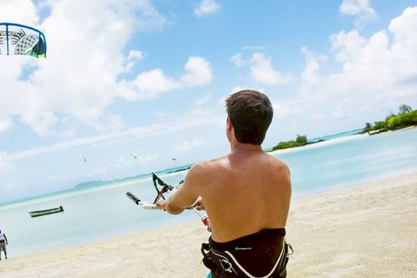 Ein Mann kitesurft am Strand, Recif Attitude Hotel im Hintergrund.