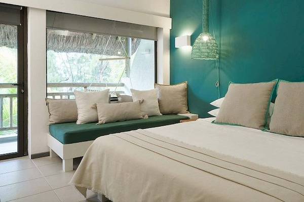 Schlafzimmer des Recif Attitude Hotels mit blauer Wand, Doppelbett, Kissen und Fenster mit Balkon.