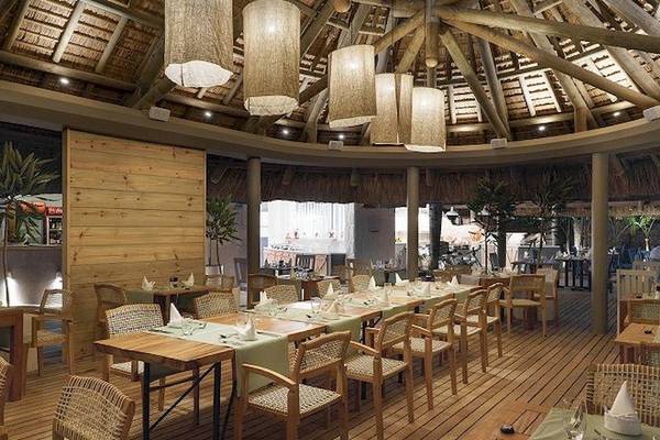 Innenansicht des Restaurants Recif Attitude mit Holztischen, Stühlen und Holzdecke.
