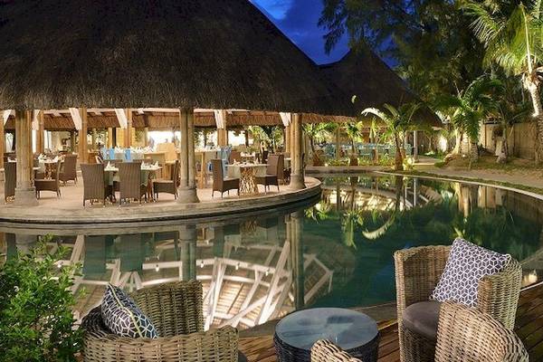 Abendstimmung am Pool des Recif Attitude Hotels mit rustikalem Gebäude und umgeben von Bäumen und Palmen.