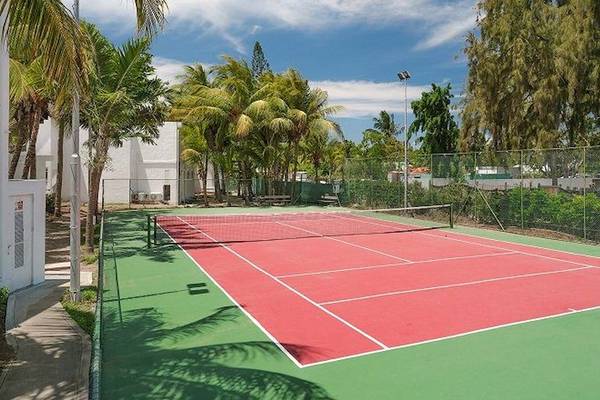 Tennisplatz im Recif Attitude Hotel, umgeben von Palmen und Bäumen.