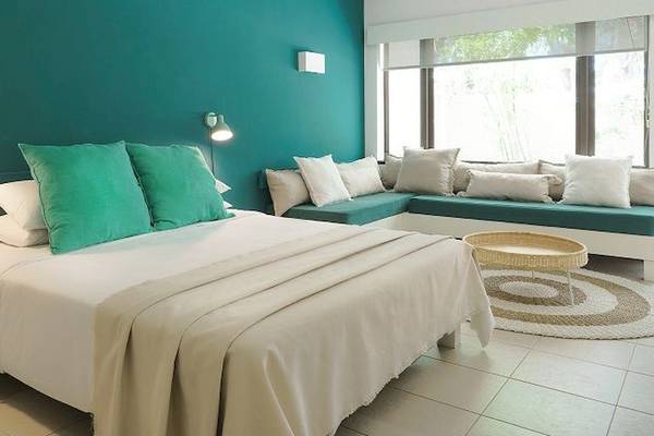 Schlafzimmer im Recif Attitude Hotel mit türkisen Wänden, weißen Möbeln und grünen Kissen