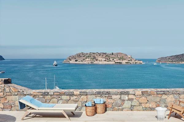 Aussicht auf das Meer vom Blue Palace Resort & Spa mit Liege, Stühlen und Körben.