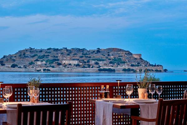 Aussicht auf die Insel vom Blue Palace Resort & Spa mit gedeckten Tischen und einer atemberaubenden Aussicht auf das Meer.