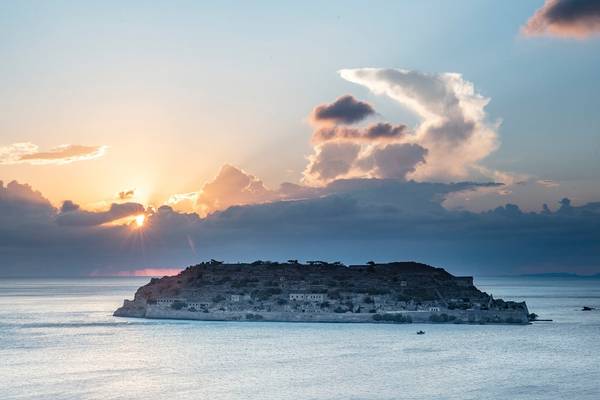 Sonnenuntergang über einer kleinen Insel im Meer mit einem wolkenreichen Himmel