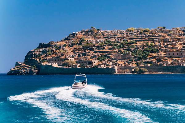 Ein Boot fährt vor einer alten Festung auf einer griechischen Insel.