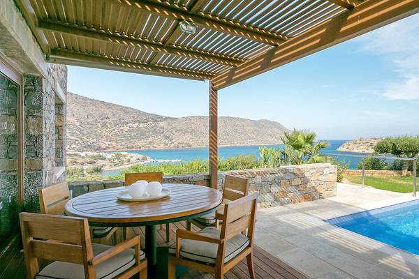 Aussicht auf den Pool vom Balkon des Blue Palace Resort & Spa mit Bergpanorama im Hintergrund.