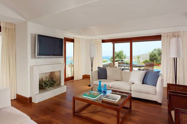 Wohnzimmer im Blue Palace Resort mit Fernseher, Kamin, Couch und Meerblick.