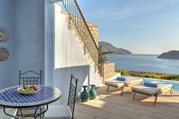 Aussicht auf das Meer vom Balkon des Blue Palace Resort & Spa mit Tisch, Liegen und Dekor.