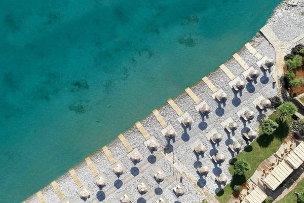 Luftaufnahme des Strandbereichs des Blue Palace Resort & Spa mit Sonnenliegen und Bäumen
