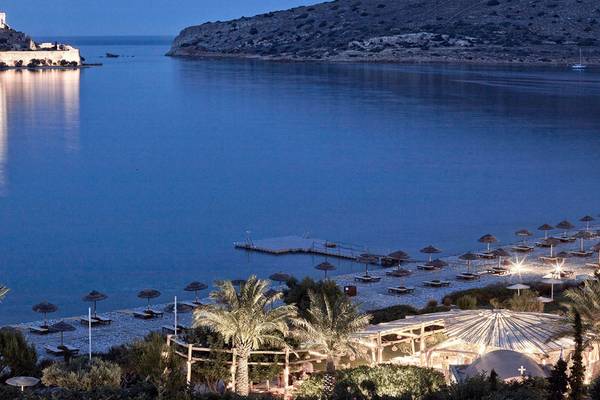 Aussicht auf das Blue Palace Resort & Spa bei Nacht mit einer Burg im Hintergrund und einem ruhigen Meer.