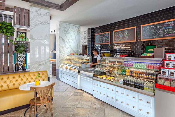 Ein Blick in den Innenbereich des IC Santai Family Resorts, wo eine Angestellte hinter einer Theke steht und verschiedene Desserts anbietet.