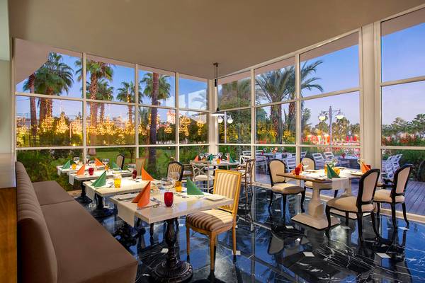 Innenansicht des Restaurants im IC Santai Family Resort mit großen Fenstern und Blick auf Palmen und Palmen.