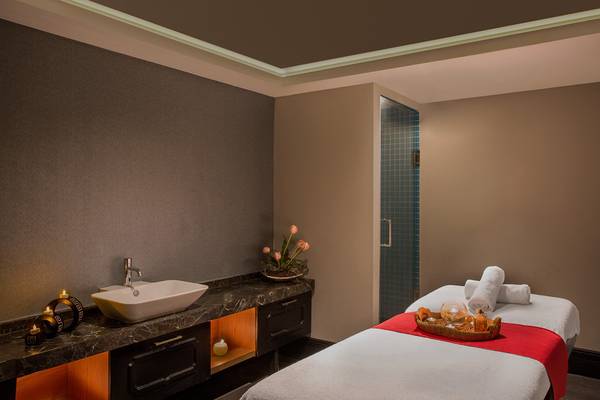 Massageraum im IC Santai Family Resort mit Tisch, Sessel, Waschbecken und Kerzen.