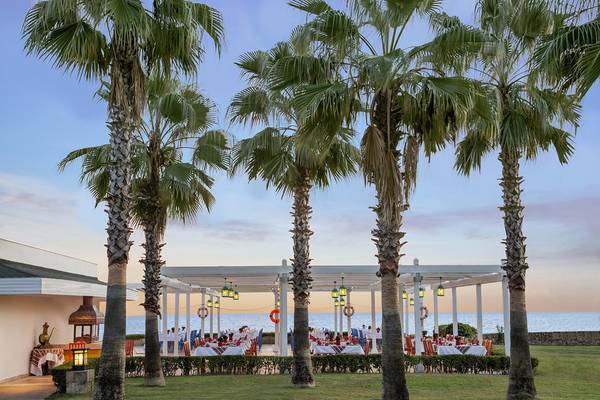 Außenbereich des IC Santai Family Resorts am Abend mit Palmen und Tischen am Meer