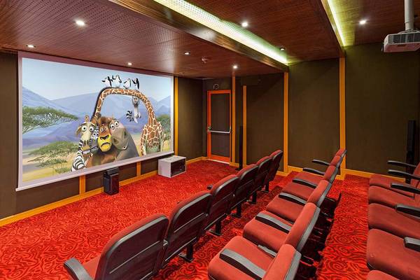 Kinosaal im IC Santai Family Resort mit roter Teppichboden und animiertem Film auf Leinwand