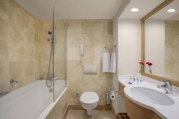 Badezimmer im IC Santai Family Resort mit Badewanne, Toilette, Waschbecken und Spiegel.