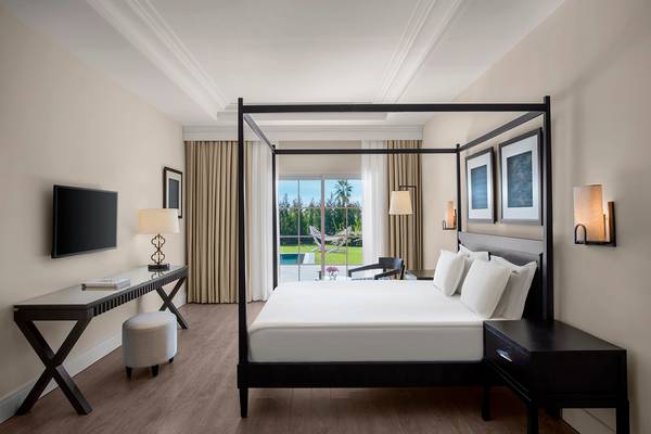 Schlafzimmer im IC Santai Family Resort mit einem Himmelbett, Fernseher, Schreibtisch und einem Fenster mit Poolblick.