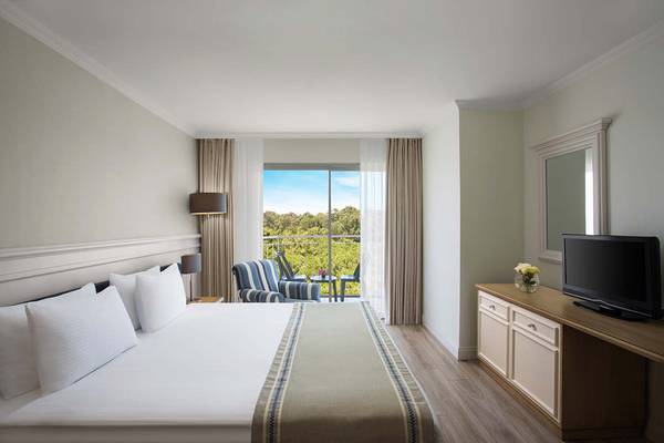 Ein modernes Hotelzimmer im IC Santai Family Resort mit Blick auf einen Balkon und einen Garten.