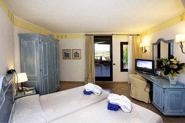 Zwei Betten im Schlafzimmer des Abi d'Oru Beach Hotel mit blauen Möbeln und einem Fernseher.